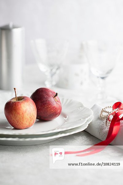 Rote Äpfel auf Teller,  Serviette mit rotem Band gebunden