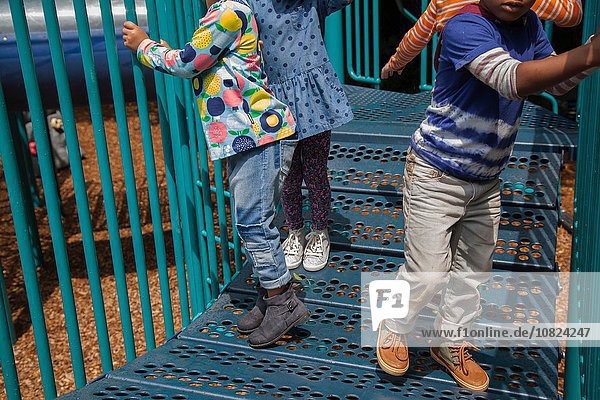Schnappschuss von vier Jungen und Mädchen  die auf einem Klettergerüst auf dem Spielplatz spielen.