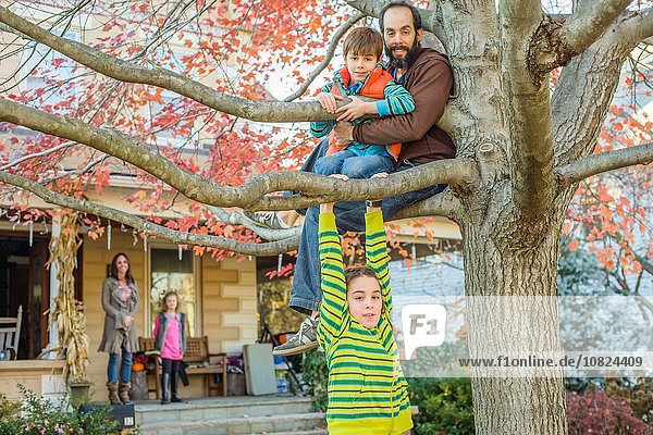 Father and children climbing tree in garden