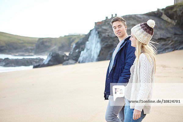 Junges Paar  das Hand in Hand am Strand spazieren geht  Constantine Bay  Cornwall  UK