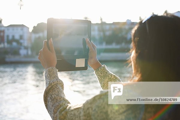 Reife Touristin beim Fotografieren des Flusses Guadalqivir auf digitalem Tablett  Sevilla  Spanien