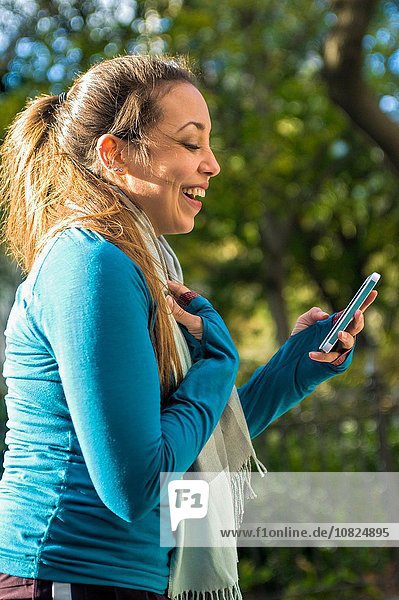 Young woman smiling at message on smartphone in park
