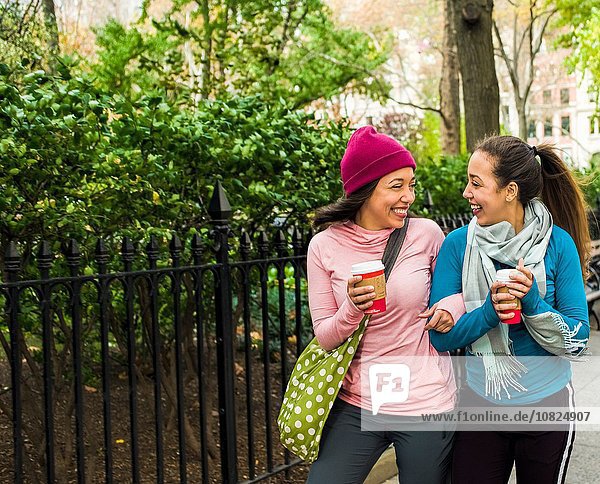 Twins walking with coffee in park