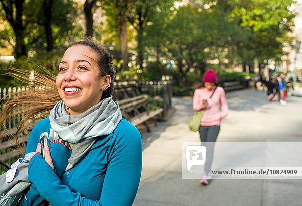 Junge Frau beim Gehen und Lächeln im Park