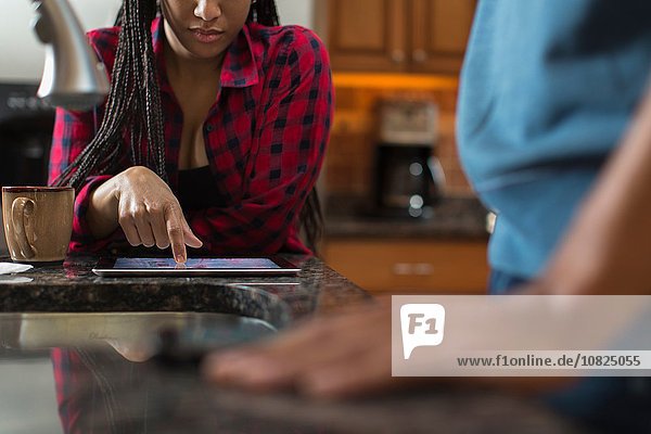 Mittleres erwachsenes Paar mit digitalem Tablett an der Küchenzeile