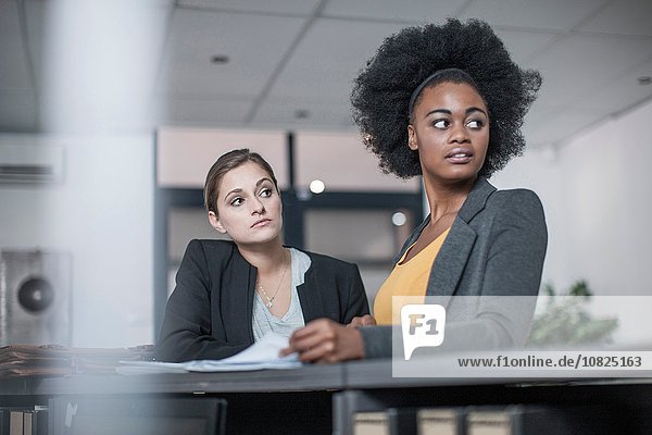 Two young businesswomen distracted at office reception