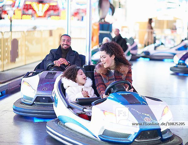 Mother and daughter in bumper car face to face smiling