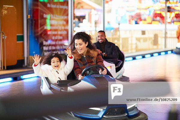 Mother and daughter in bumper car arms raised smiling