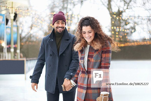 Couple on ice rink holding hands smiling