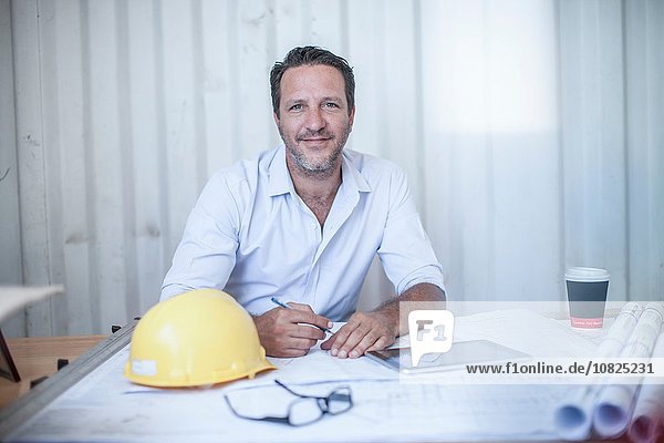 Portrait of male construction foreman at desk in portable cabin