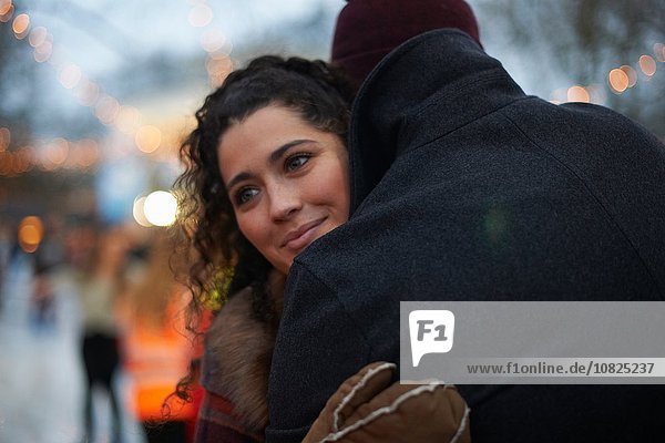 Young woman hugging mid adult man looking away smiling
