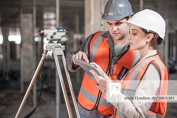 Female and male surveyor using digital tablet on construction site