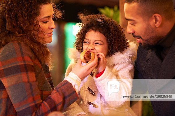 Mother and father feeding daughter hot dog