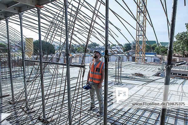 Site manager looking up at steel rod structures on construction site