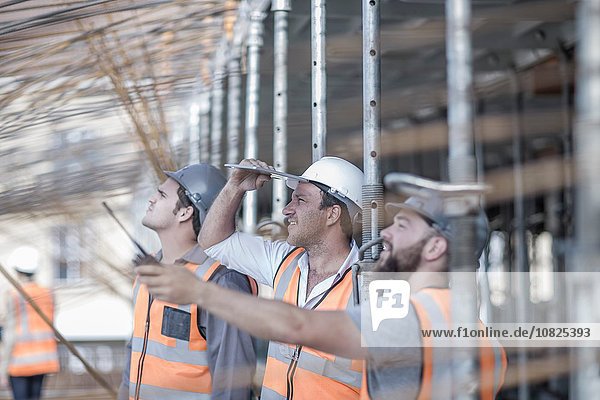 Site manager and builders looking up at steel rod structure on construction site