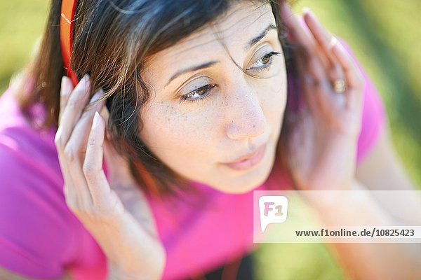 Abgeschnittene Hochwinkelansicht einer reifen Frau mit Kopfhörer  Hände auf den Ohren  die wegschauen
