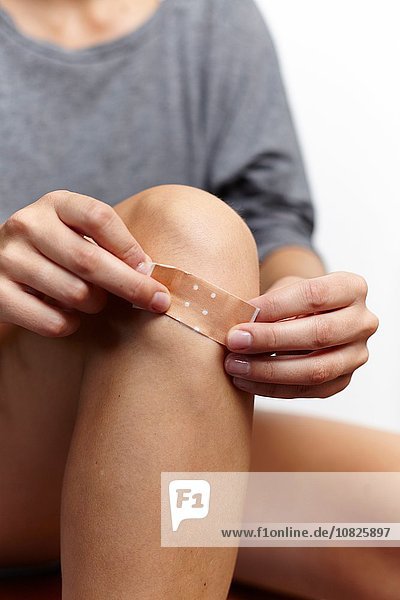 Woman applying plaster on knee