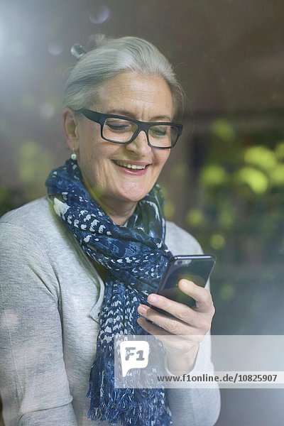 Reife Frau lächelt über die Nachricht auf dem Smartphone