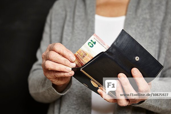 Eine Frau  die Geld aus ihrer Brieftasche holt.