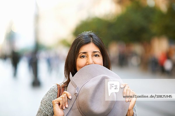 Frau mit Hut über dem Mund auf der Straße