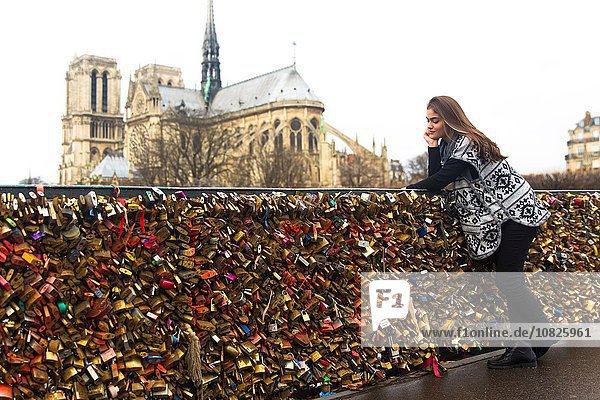 Junge Frau lehnt sich an Liebesschleusen  Pont de l'archeveche  Kathedrale Notre Dame im Hintergrund  Paris  Frankreich