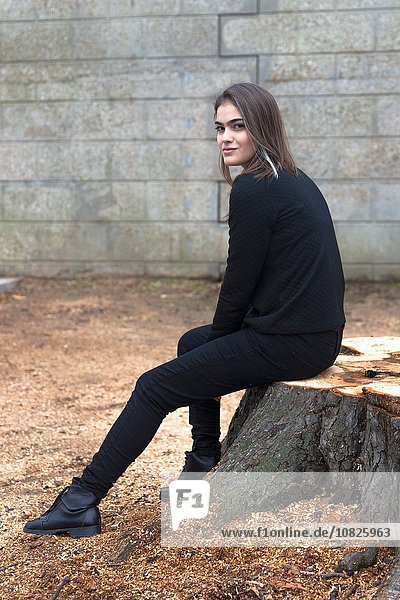 Young woman sitting on tree stump