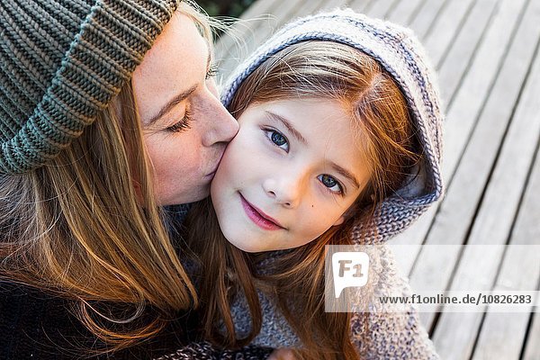 Mother kissing daughter on cheek  high angle portrait