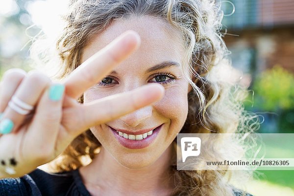 Junge Frau macht Friedenszeichen mit der Hand