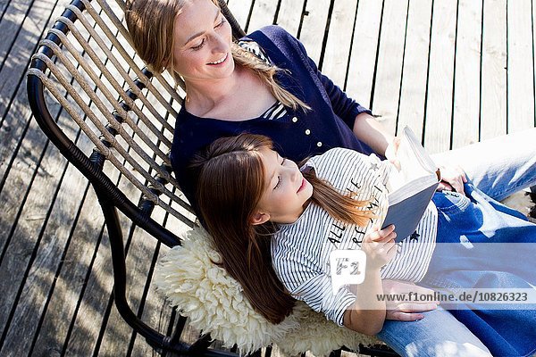 Mutter und Tochter entspannen sich auf dem Sessel  Mädchen lesen Buch