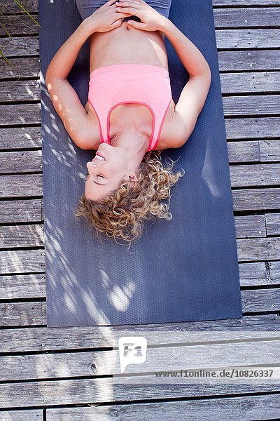 Junge Frau auf Yogamatte liegend  hoher Winkel