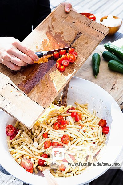 Frau schabt Tomaten in Schüssel mit Messer