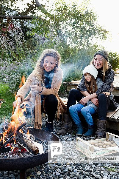 Zwei Frauen und ein Mädchen  die am Feuer sitzen und sich entspannen.