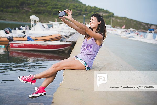 Frau an der Küste  nimmt Selfie mit Smartphone