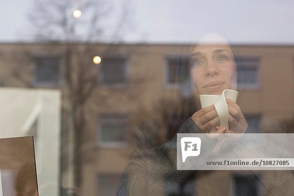 Junge Frau  die durch das Caféfenster blickt