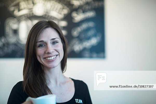Porträt einer jungen Kellnerin mit Kaffee im Café