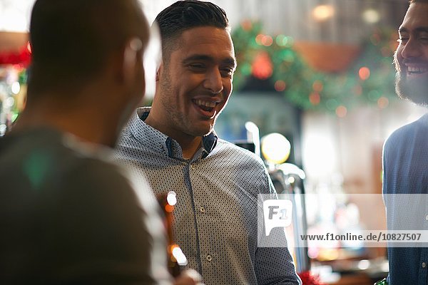 Young man in public house with friends smiling