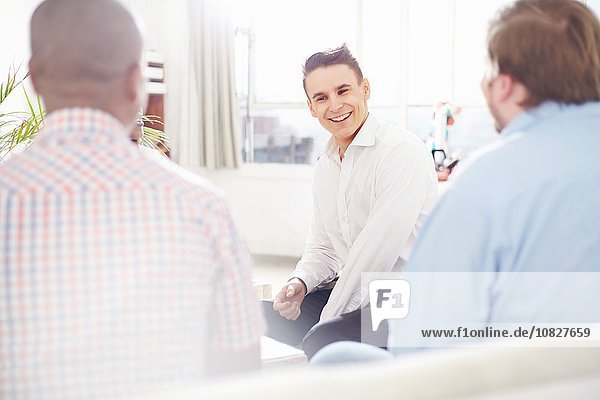 Young man in office talking to colleagues smiling