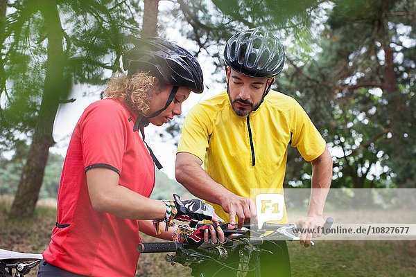 Mountainbike-Paar beim Prüfen des Fahrradlenkers im Wald