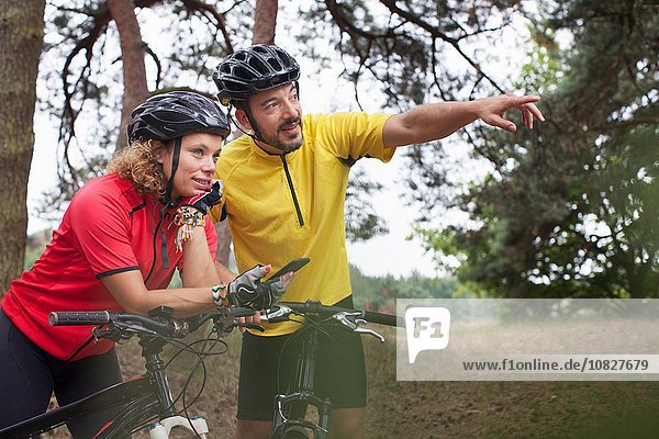 Mountain biking couple using smartphone navigation in forest