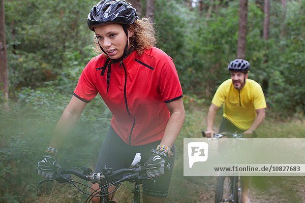Mountain biking couple biking through forest