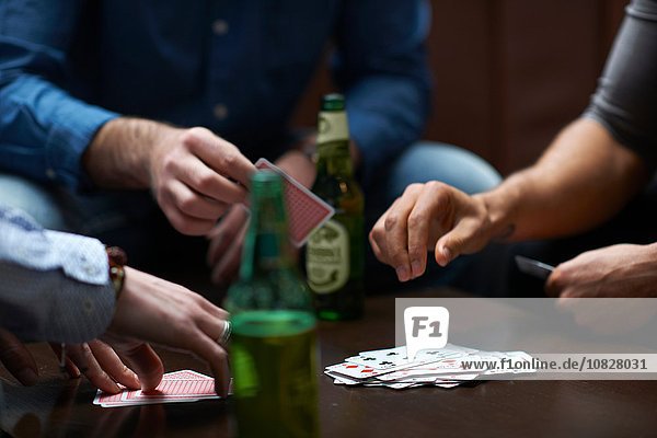 Hands of three men playing card game in traditional UK pub