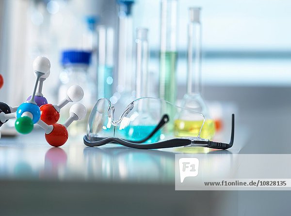 Schutzbrille und molekulares Modell auf Labortisch  wissenschaftliche Ausstattung im Hintergrund