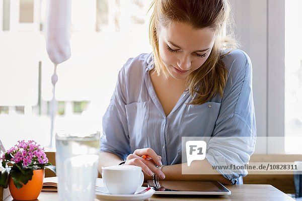Young woman in cafe writing  looking at camera smiling