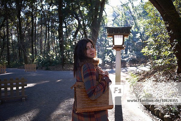 Porträt einer reifen Touristin mit Blick über die Schulter im Park  Tokio  Japan