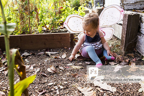 Kaukasisches kleines Mädchen mit Feenflügeln im Garten