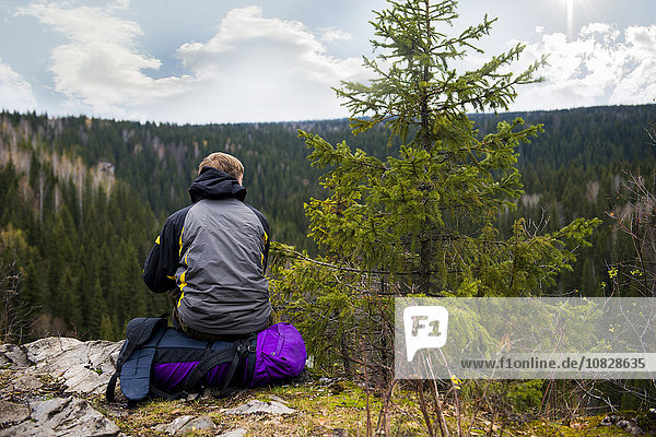 Kaukasischer Wanderer auf einer abgelegenen Bergkuppe sitzend