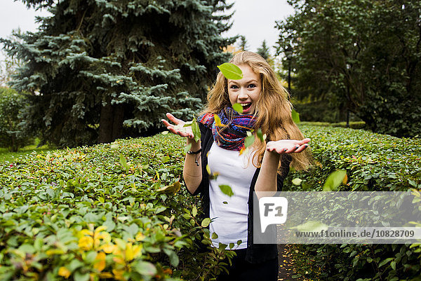 Kaukasische Frau wirft Blätter im Garten