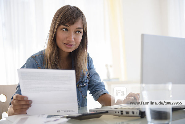 Mixed race woman paying bills on laptop
