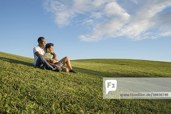 Vater und Sohn sitzen im Gras