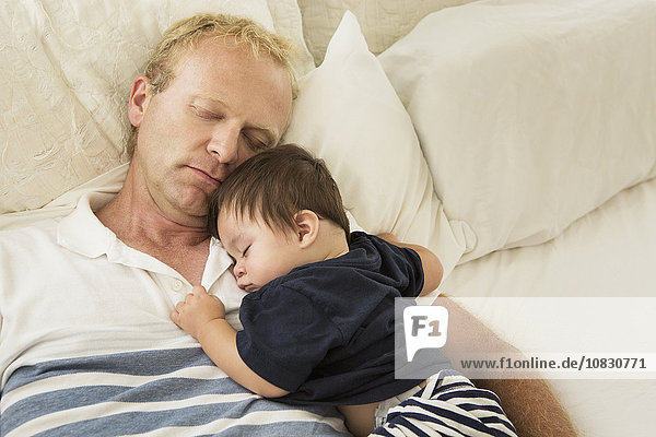 Father and baby son sleeping on bed